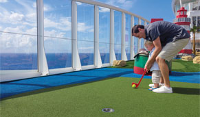 Familia disfrutando de una partida de mini golf a bordo de un crucero. CrucerosMediterraneo.com Familia disfrutando de una partida de mini golf a bordo de un crucero. CrucerosMediterraneo.com