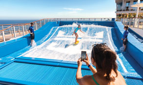 Cruceros familiares por el Mediterráneo, niña disfrutando del simulador de surf a bordo. CrucerosMediterraneo.com