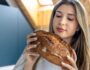 Woman examines fresh homemade bread in kitchen. Bread aroma.