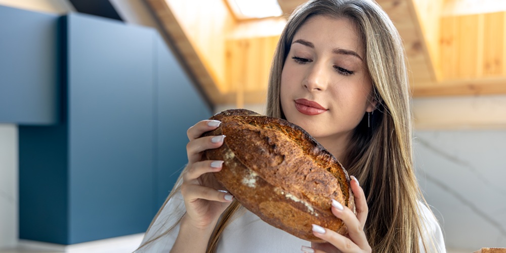 Woman examines fresh homemade bread in kitchen. Bread aroma. Woman examines fresh homemade bread in kitchen. Bread aroma.