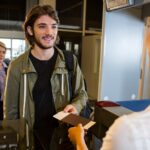 Man in queue receiving passport and boarding pass at airport terminal