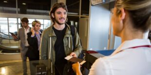 Man in queue receiving passport and boarding pass at airport terminal