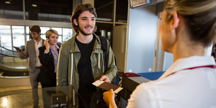 Man in queue receiving passport and boarding pass at airport terminal