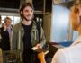 Man in queue receiving passport and boarding pass at airport terminal